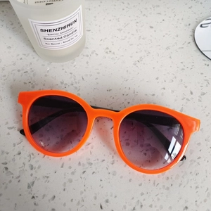 Vue à plat de lunettes de soleil rondes orange vif avec verres dégradés sur pierre