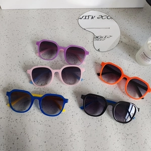 Five pairs of trendy colorful geometric square sunglasses set on a stone surface