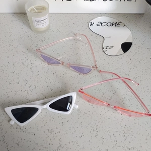 Retro triangle cat-eye kids sunglasses in white and pink frames on stone surface
