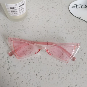 Detailed shot of pink transparent triangular cat-eye kids sunglasses on stone texture