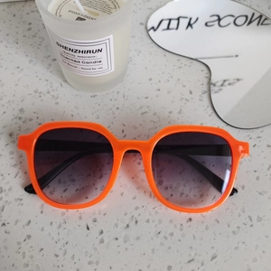 Top view of bright orange square sunglasses with gradient lenses on a marble surface