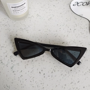 Close-up of black triangle cat-eye sunglasses for kids on a white stone background