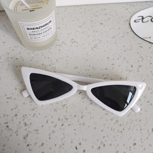 Close-up of retro white triangle kids sunglasses with black lenses on a textured surface