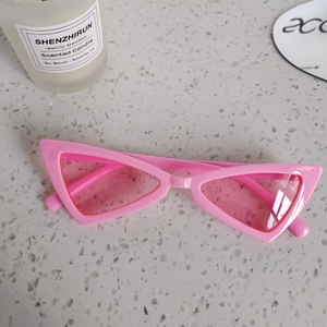 Detail of pink triangle cat eye sunglasses for kids on a textured grey background