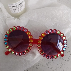 Detail of red round sunglasses frame encrusted with vibrant colorful rhinestones