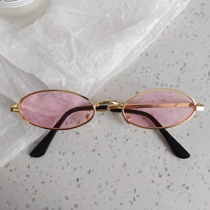 Détail de lunettes de soleil coeur enfant avec verres roses et monture en métal doré