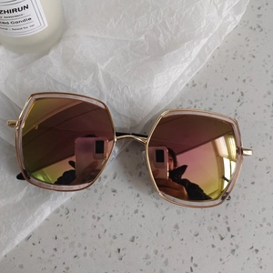 Détail de lunettes de soleil géométriques en métal doré avec verres dégradés rose doré