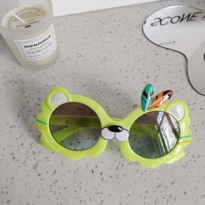 Detail shot of bright green animal-shaped kids sunglasses with cute ear and feather accents