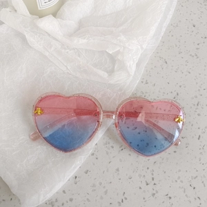 Detail of heart-shaped sunglasses featuring pink-blue gradient lenses and bee accent
