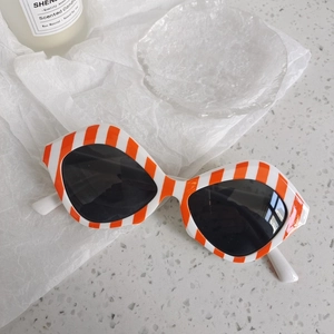 Détail de lunettes de soleil rondes rayées orange et blanc avec verres gris foncé