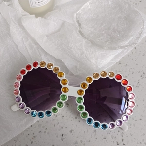 Détail de lunettes de soleil rondes blanches avec strass arc-en-ciel et verres violets