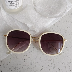 Détail de lunettes de soleil rétro blanches avec branches dorées et verres dégradés