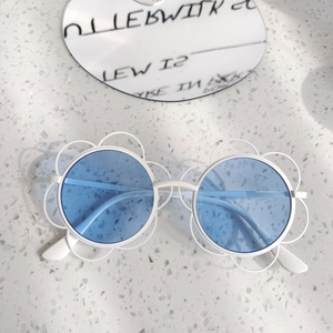 Dettaglio occhiali da sole bianchi a fiore per bambini con lenti blu tonde su marmo