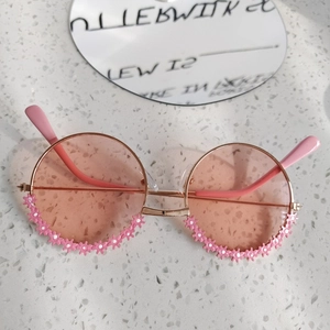 Dettaglio occhiali da sole per bambini a fiore con lenti rosa e montatura in metallo decorata