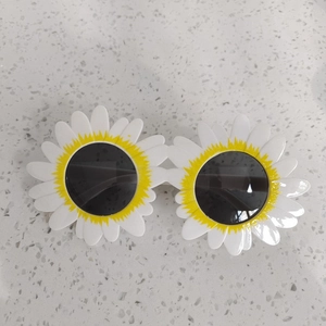 Dettaglio di occhiali da sole per bambini a forma di girasole bianco con petali gialli