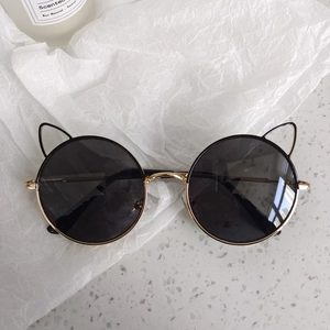 Détail des lunettes de soleil oreilles de chat avec monture ronde et branches dorées