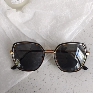 Détails de lunettes de soleil œil-de-chat noires avec des accents en métal doré