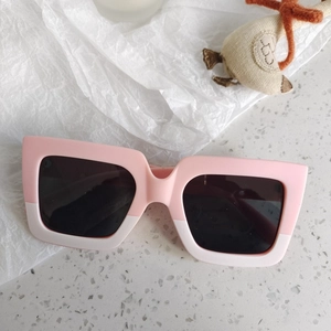 Close-up of pink and cream dual-tone matte square sunglasses for kids with dark lenses