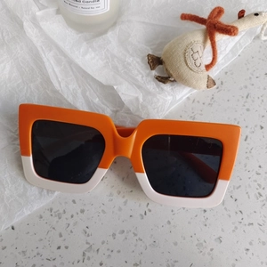 Detail of square oversized orange and cream children's sunglasses with dark lenses