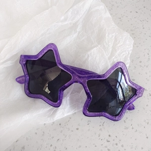 Close-up of purple star-shaped sunglasses with sparkling glitter finish for kids