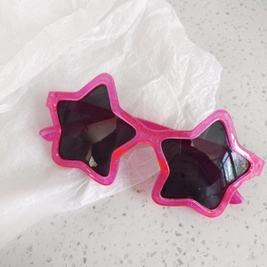 Macro detail of star-shaped pink glitter sunglasses for kids with dark tinted lenses