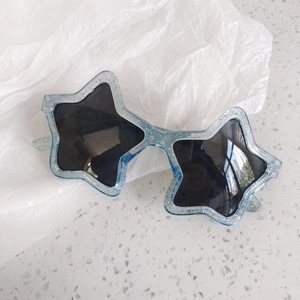Detail of star-shaped children's sunglasses with blue glitter frame and dark lenses