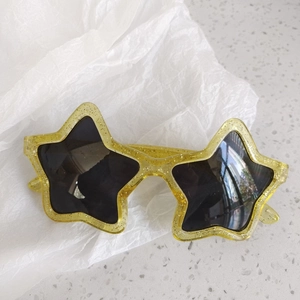 Close-up of star-shaped kids' sunglasses in transparent yellow with golden glitter details