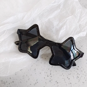 Detailed view of star-shaped sunglasses with black frame and silver glitter accents