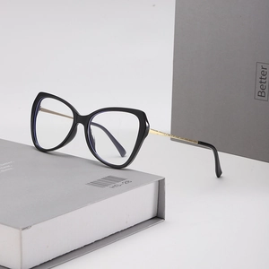 Gros plan de lunettes yeux de chat noires avec branches dorées sur un livre gris
