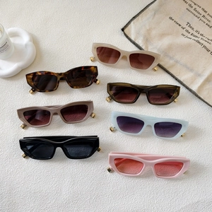 Chic cat-eye sunglasses in multiple colors with gold-tone accents on textured background