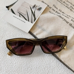 Detail of cat-eye sunglasses with translucent tea frames and gold metal hinges