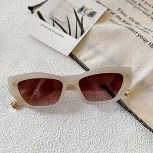 Detail of cream frame sunglasses with brown lenses and golden metal accents
