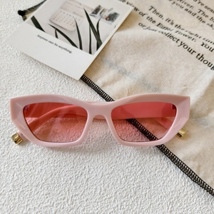 Detailed top view of pink cat-eye sunglasses with gold metal accents on white texture
