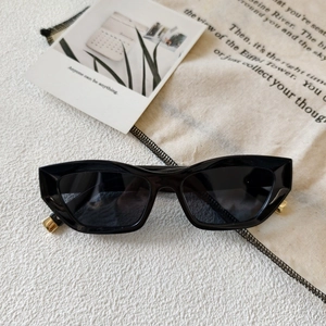 Detailed macro view of black cat-eye sunglasses with geometric frame and gold metal hinges