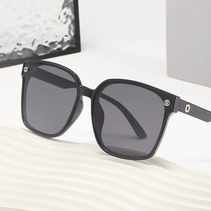 Lunettes de soleil carrées noires surdimensionnées avec logo métallique sur support blanc