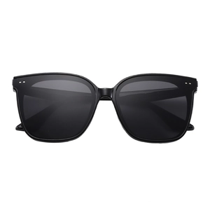 Detail of square black sunglasses with silver rivet accents on a white background