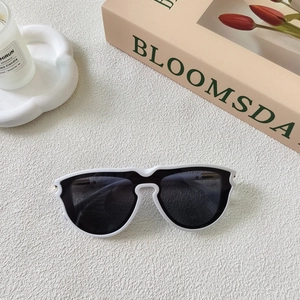 Macro shot of stylish white wavy frame sunglasses with dark lenses on a stone surface