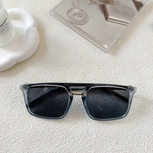 Detail of square oversized sunglasses with smoky gray frames and gold metal bridge