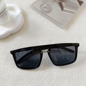 Close-up of black square sunglasses with silver metal bridge detail on a white surface