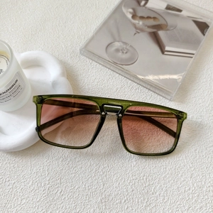 Detail of square vintage sunglasses with green transparent frames and pink gradient lenses