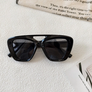 Detail of black square full-rim sunglasses with stylish hollow double bridge and dark lenses