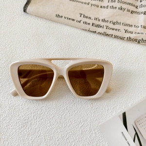 Detail of cream double-bridge sunglasses with translucent brown lenses and cat-eye frame