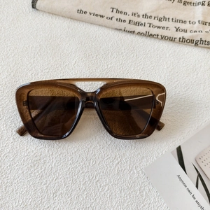 Detail of vintage brown sunglasses with a double-bridge frame on a textured background