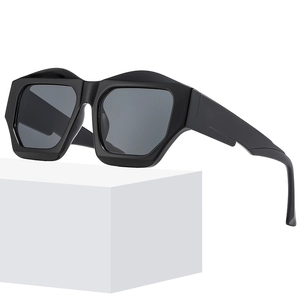 Modern chunky black geometric cat-eye sunglasses with irregular frames on a white pedestal