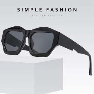 Modern irregular geometric matte black sunglasses with dark grey lenses on white pedestal