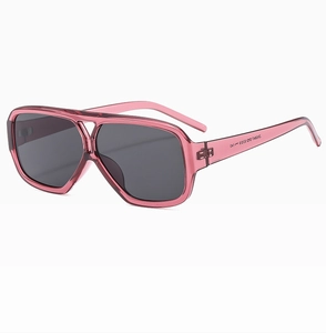 Close-up of pink translucent frame sunglasses with retro double bridge and dark lenses