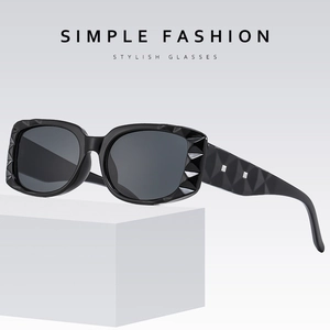 Black square sunglasses with geometric textured frame on minimalist white block pedestal
