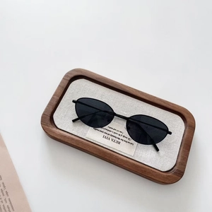 Détail de lunettes de soleil vintage ovales noires pour enfants sur un plateau en bois