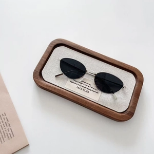 Détail de lunettes de soleil ovales en métal avec verres noirs sur plateau en bois