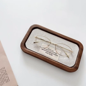Détail de lunettes de soleil dorées à monture ovale sur un plateau en bois minimaliste